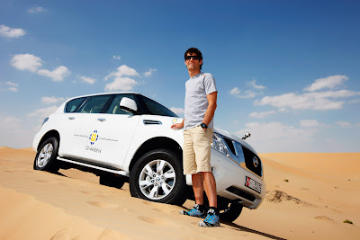 Марк Уэббер на фоне внедорожника Nissan в песчаной пустыне перед Гран-при Абу-Даби 2011