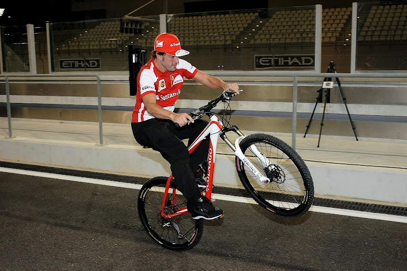 Фернандо Алонсо едет на заднем колесе на велосипеде на Гран-при Абу-Даби 2013
