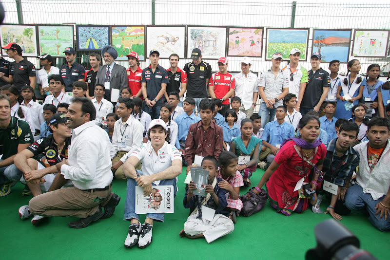 пилоты Формулы-1 с индийскими детьми на фоне рисунков на Гран-при Индии 2011