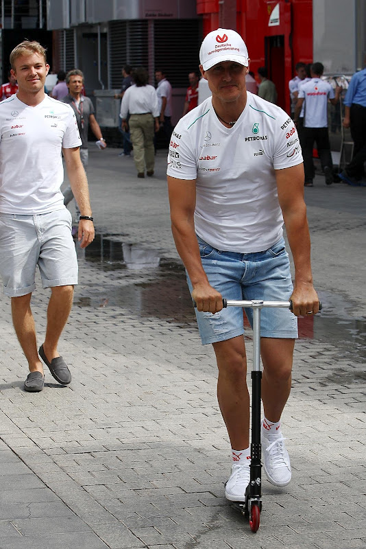 Михаэль Шумахер едет впереди Нико Росберга на самокате на Гран-при Европы 2012