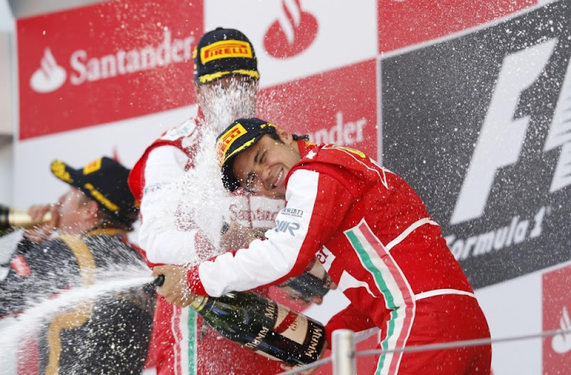 Кими Райкконен пьет шампанское, пока Фернандо Алонсо и Фелипе Масса разбрызгивают его на подиуме Гран-при Испании 2013