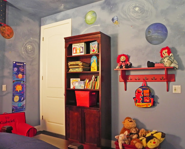 Gabriel's Bedroom - 2 of 6 - A bookcase holds favorite books and treasures. A shelf with hooks below holds his backpack and other toys.