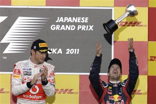 Себастьян Феттель подбрасывает свой трофей на подиуме Гран-при Японии 2011 - Дженсон Баттон аплодирует