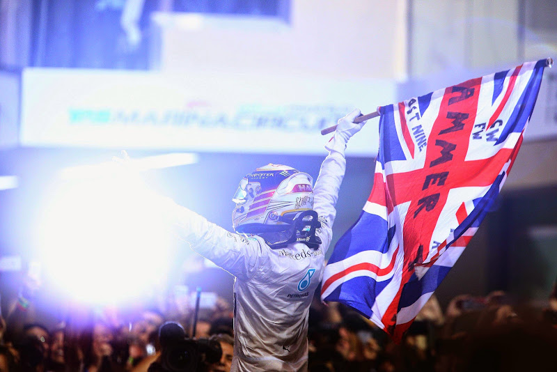 Льюис Хэмилтон c флагом празднует победу в чепионате и на Гран-при Абу-Даби 2014