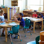 The Montessori elementary classroom looks very different from a traditional classroom. Children work at tables, alongside each other or with each other, with shelves of materials nearby.