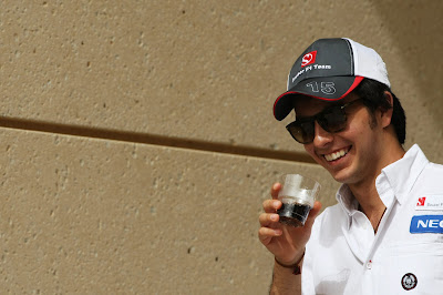 улыбающийся Серхио Перес выпивает из стаканчика на Гран-при Бахрейна 2012