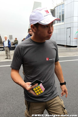 Камуи Кобаяши идет по паддоку Хунгароринга с Кубиком Рубиком в руках на Гран-при Венгрии 2011