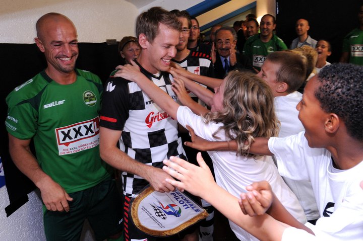 поклонники обнимают Себастьяна Феттеля на футбольном матче в дни уикэнда Гран-при Германии 2011