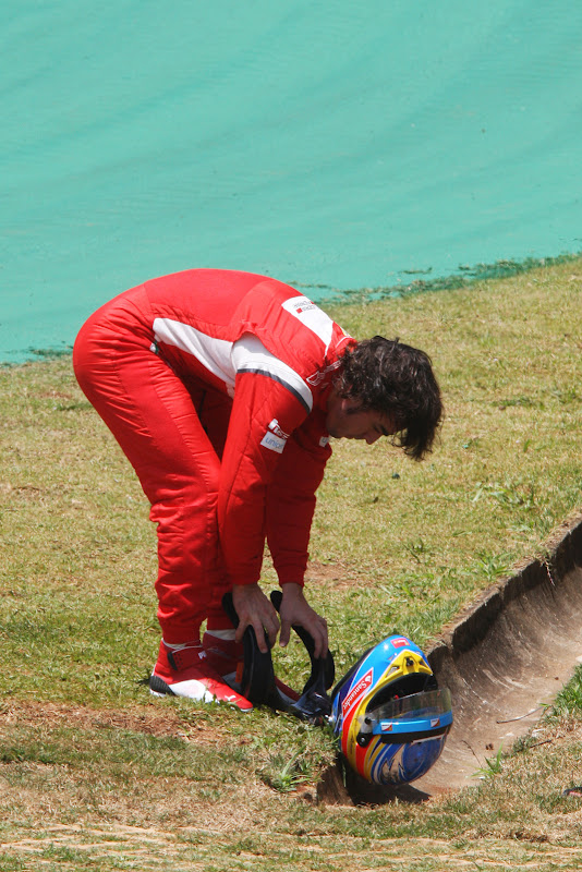 Фернандо Алонсо кладет шлем на землю после схода во во время первой сессии свободных заездов на Гран-при Бразилии 2011