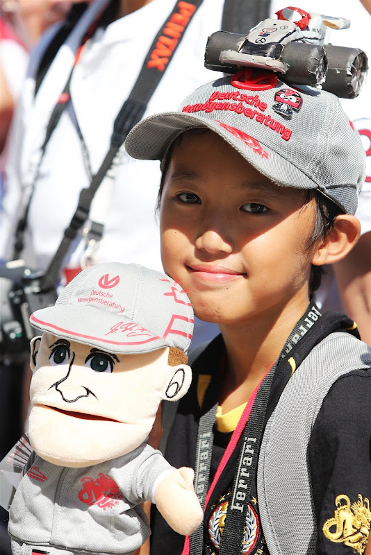 болельщица Михаэля Шумахера и Mercedes с куклой и мини-болидом на кепке на Гран-при Японии 2012
