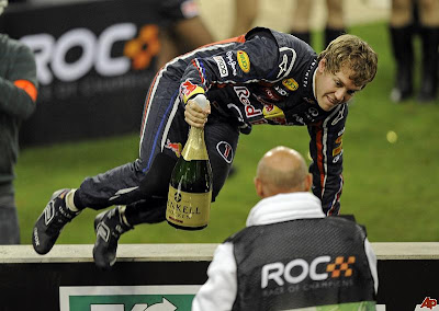 Себастьян Феттель перепрыгивает через ограждение с бутылкой шампанского на Гонке чемпионов 2011