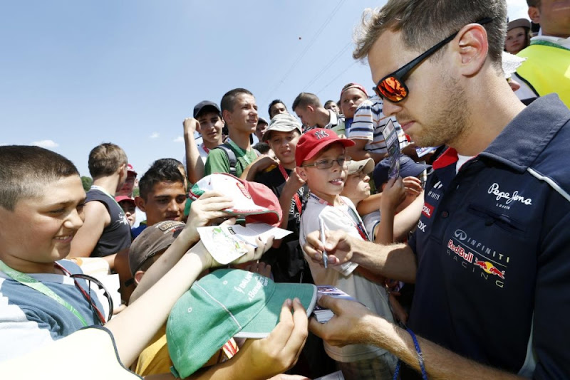 Себастьян Феттель раздает автографы на трибуне с болельщиками на Гран-при Венгрии 2013