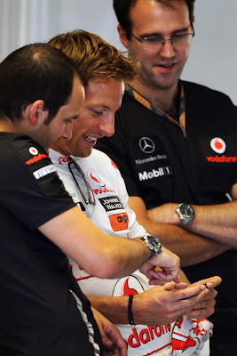 Дженсон Баттон показывает что-то забавное на телефоне механикам на Гран-при Италии 2011
