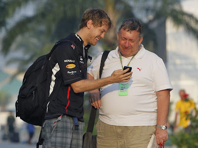 Себастьян Феттель показывает что-то на своем телефоне на Гран-при Малайзии 2012