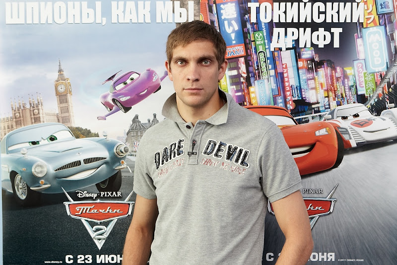 Виталий Петров на фоне постера Тачки 2