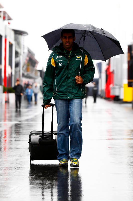 Карун Чандхок под зонтиком с чемоданом в паддоке Нюрбургринга на Гран-при Германии 2011