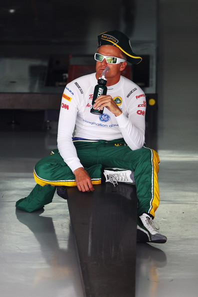 Хейкки Ковалайнен сидит в гараже в кепка набок на Гран-при Бразилии 2011