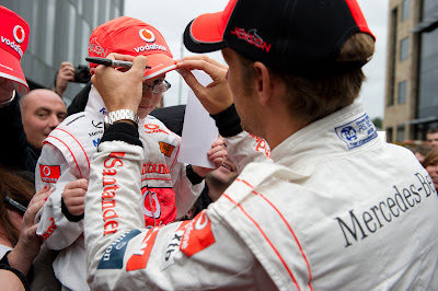 Дженсон Баттон подписывает кепку мальчику в комбинезоне McLaren на автограф-сессии Vodafone в Манчестере 29 августа 2011