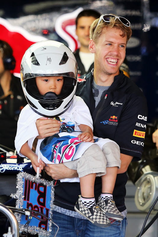 Себастьян Феттель несет на руках своего болельщика в боксы Red Bull на Гран-при Японии 2012