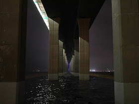A view over the water at night underneath the Zhanjiang Bay Bridge.