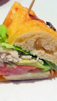 Details of the Avocado Turkey bagel sandwich at Nuvrei Patisserie and Cafe, here on a cheddar jalapeno bagel with avocado, turkey, tomato, red onion, butter lettuce, choice of bagel that is made with some homemade pretzel dough and cream cheese of course