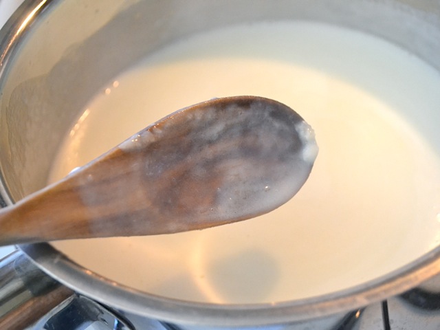 thickened white sauce on wooden spoon 