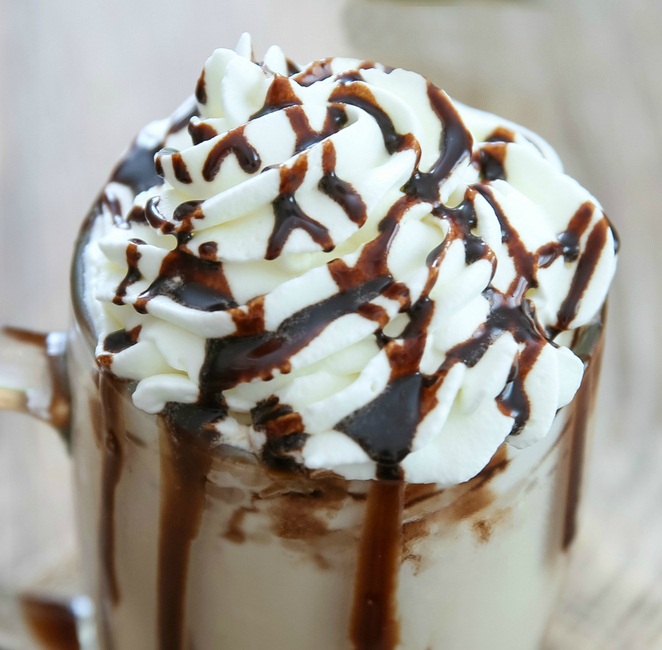 a close-up photo of whipped cream topping with chocolate sauce drizzled over the top