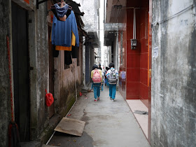 elementary school girls walking down a narrow pedestrian alley in Yangjiang, China