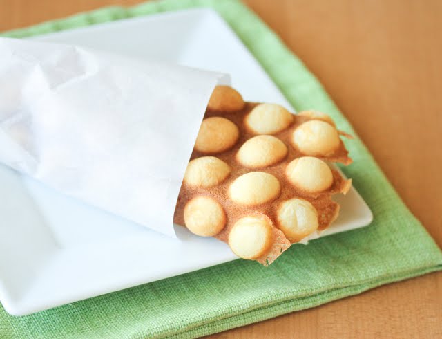 egg waffle wrapped in paper on a white plate