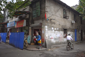 man riding a bike next to a building marked for demolition at Beizheng Street in Changsha, China