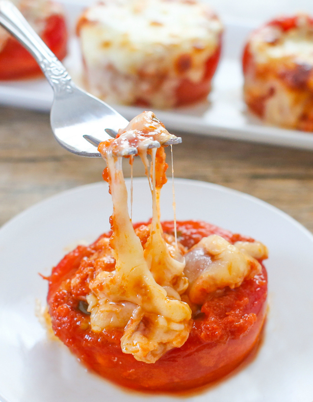 photo of a fork pulling up melted cheese on a tomato