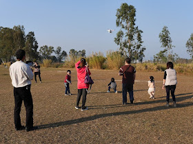 man operating a small quadcopter drone as adults and kids watch