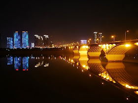 evening view of a bridge over Changsha's Xiang River with brightly lit buildings in the background