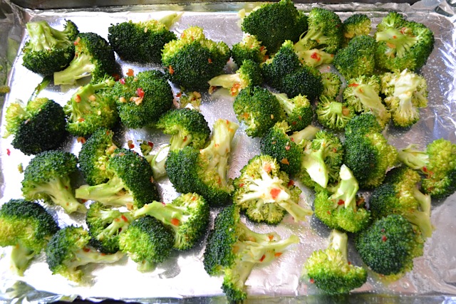 seasoned and coated broccoli placed on baking sheet lined with tin foil 