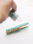 Glitter time! Lay your clothespin down on a piece of scrap paper, sticky side up (the scrap paper will come in handy for saving the leftover glitter).