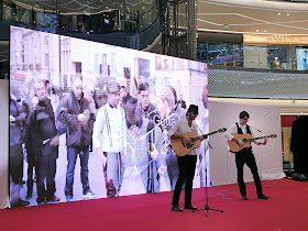 two men playing guitar in front of a video display
