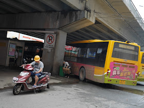 mototaxi driver sitting on a motorbike under a bridge