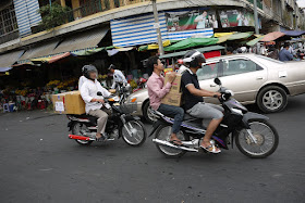people carrying boxes while riding motorbikes in Phnom Penh