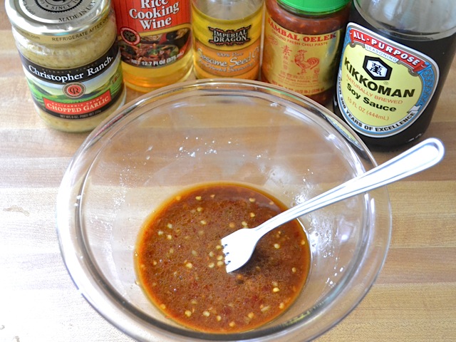 kung pao sauce in mixing bowl with bottles of ingredients in background