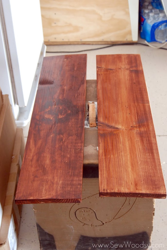 Two 2x10 stained wood boards resting on a block.
