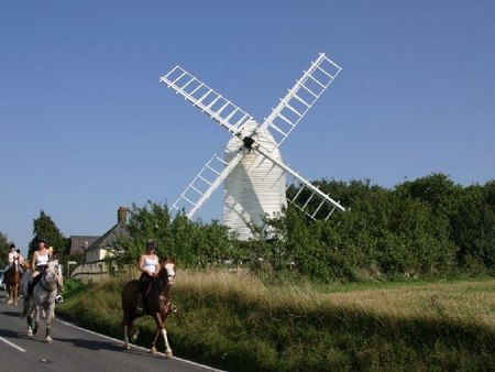 Horse riders passing windmill