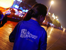 girl wearing a light jacket with the words "WASSUP SHOW OFF" on the back