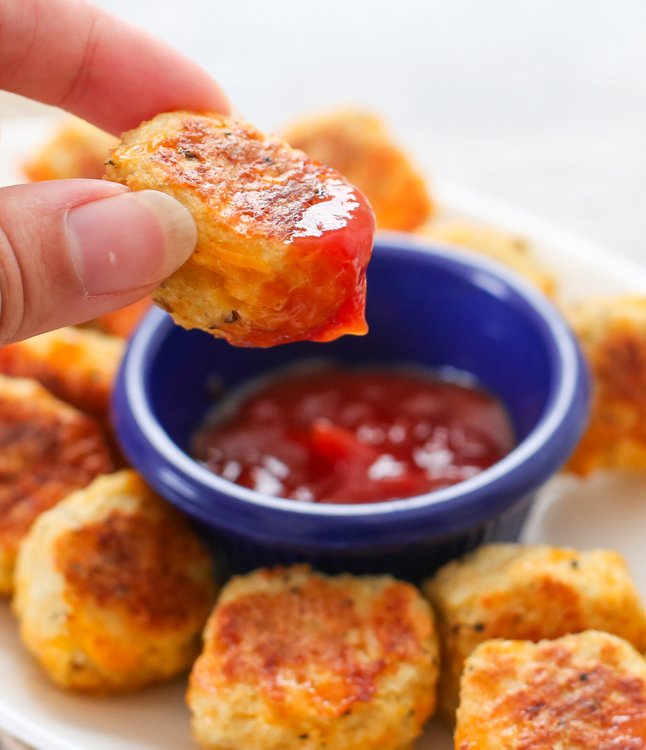 a close-up photo of a cauliflower tot dipped in sauce