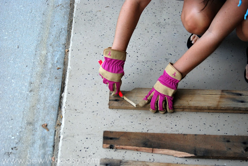 Female in gloves tracing wood on top of another piece of wood. 