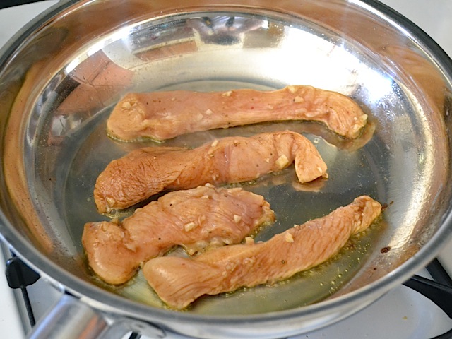 chicken strips placed in hot skillet with oil 