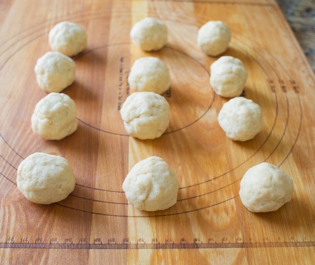 a process photo showing biscuit dough balls lined up on a cutting board