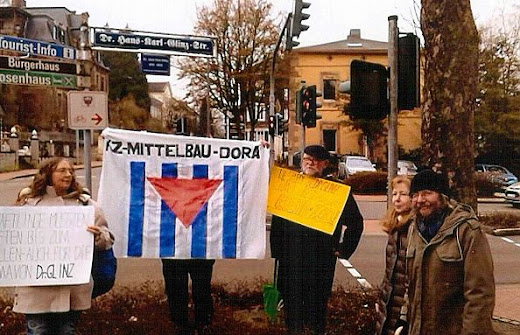Protestler vor Straßenschild mit VVN-Fahne und Transparenten.