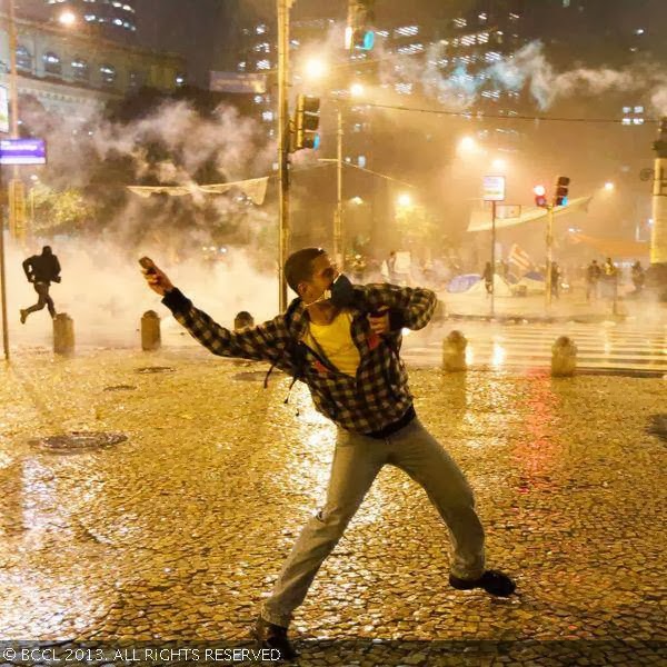 A demonstrator from the group called Black Bloc throws a stone as he clashes with riot police outside of the Municipal Assembly during a protest supporting a teachers' strike in Rio de Janeiro.