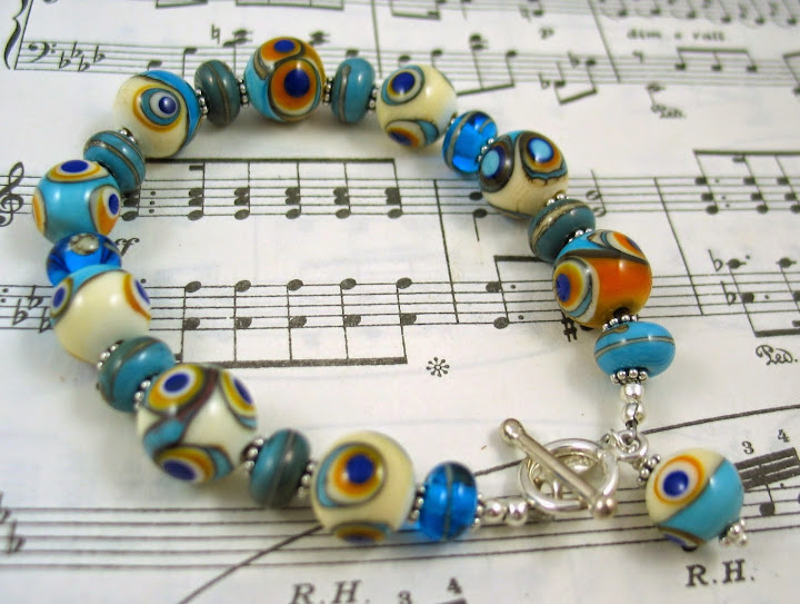 Egyptian Priestess Magic Eye Beads – these were inspired by beads found intact in necklace form on the 2000 + year old remains of an Egyptian goddess. She was buried wearing her magic beads – believed to be that way because of the colours used (lapis, ochre, turquoise) and the “eye” design.. Artist Lesley McIver