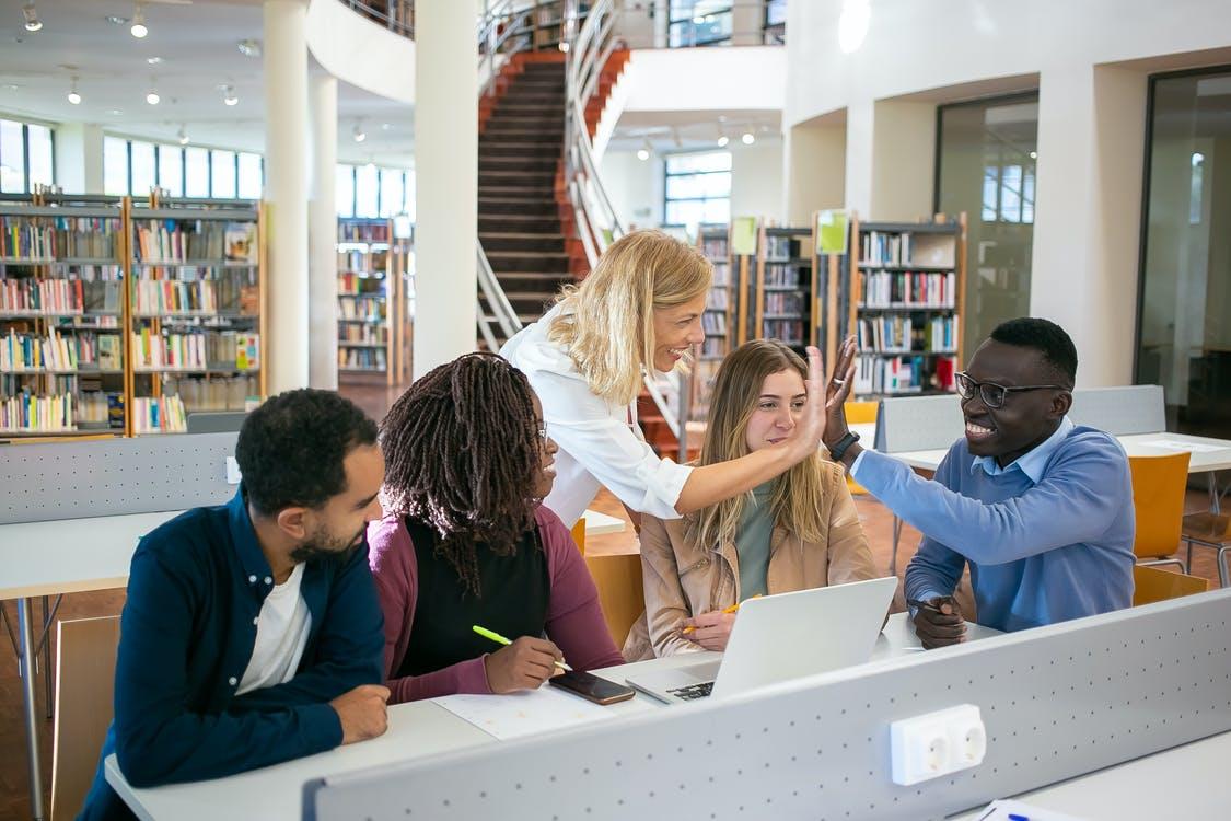 Students working in a library and high-fiving